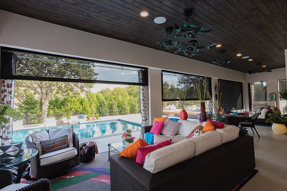 Sleek exterior roller shades filtering in light to a poolside patio.