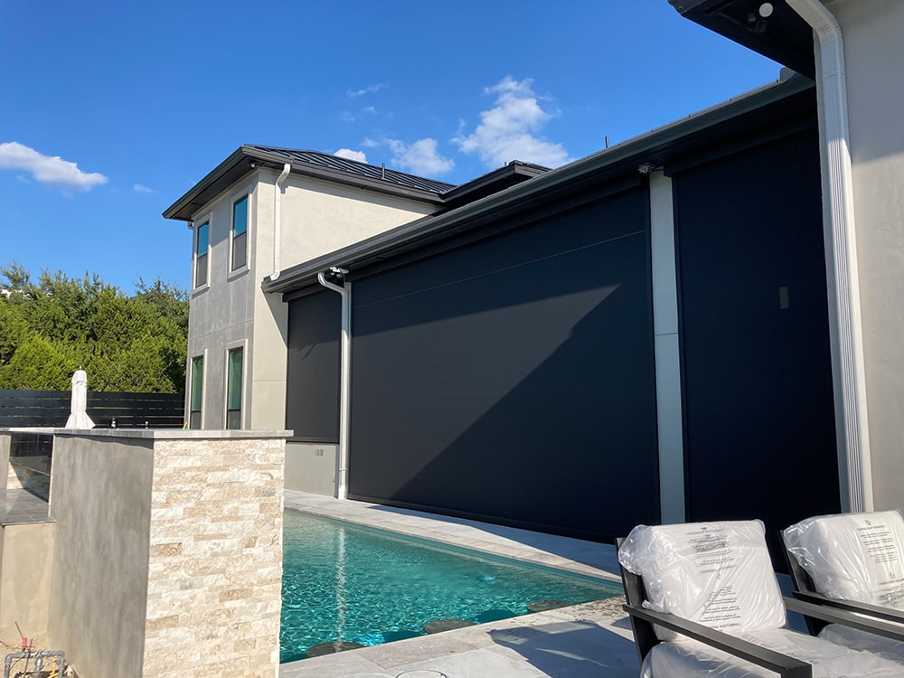 Blackout exterior shades enclosing a back patio next to a backyard pool.