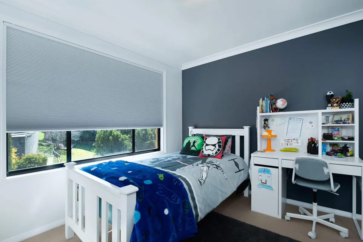 Gray cellular shades on a large bedroom window overlooking green landscaping in Venice, FL