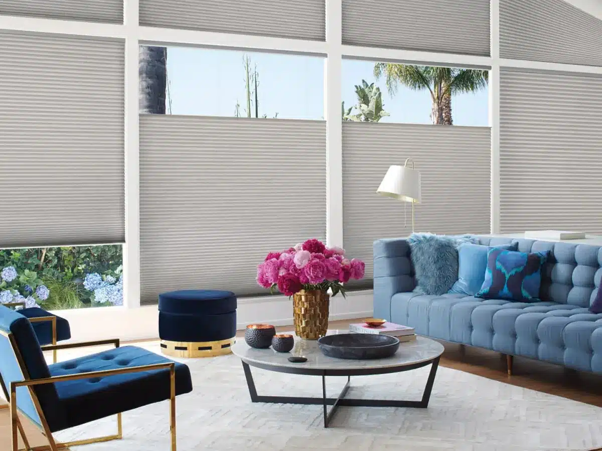 Modern living room with cellular shades covering large windows overlooking palm trees and garden in Venice, FL