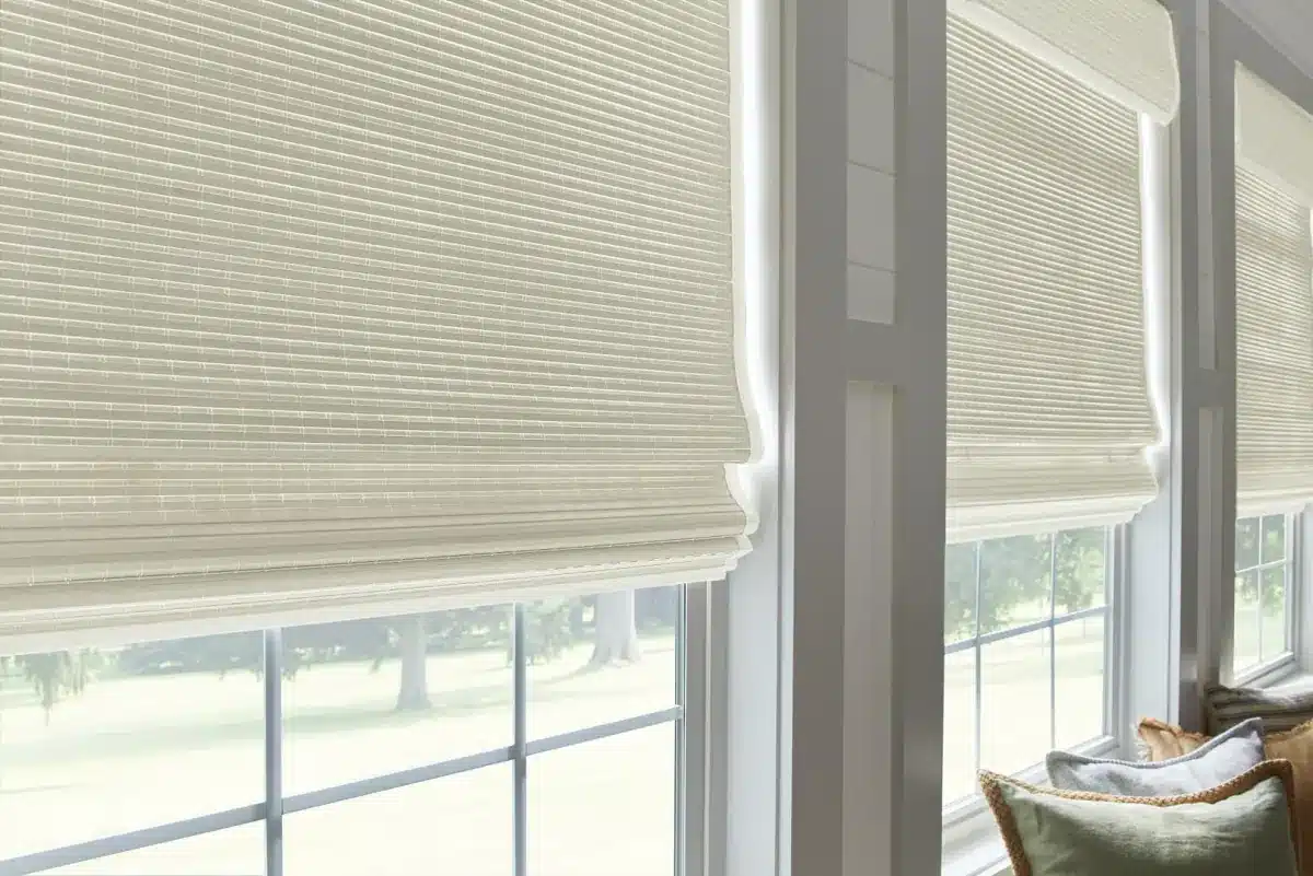 Cream cellular shades on large windows overlooking a sunny landscape with green lawn and trees in Venice