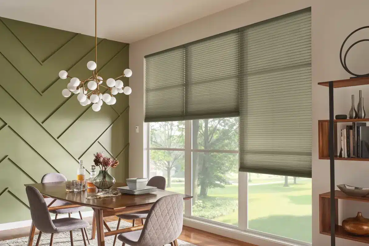Gray cellular shades on large dining room windows overlooking green lawn and trees in Venice, FL