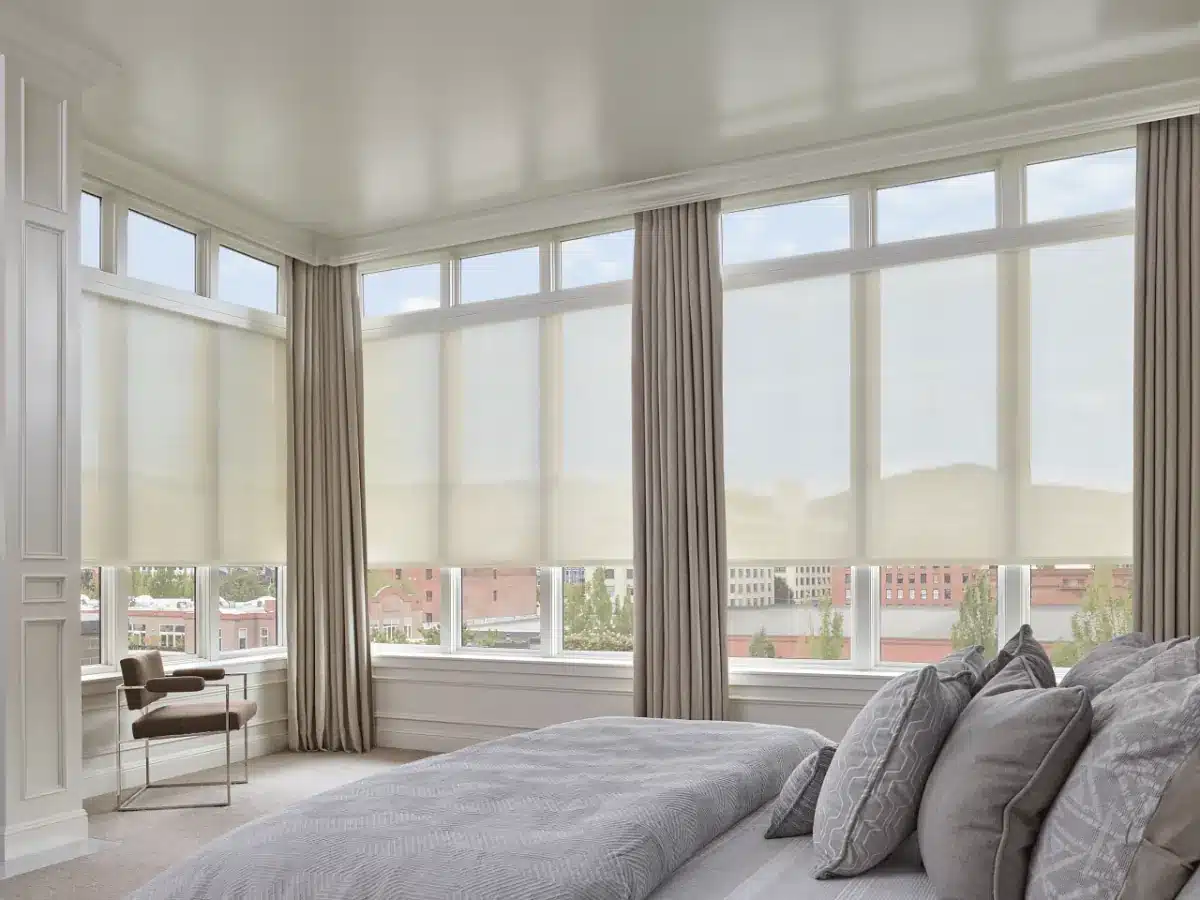 Modern bedroom with floor-to-ceiling custom drapery and sheer panels overlooking a city skyline in Venice, FL