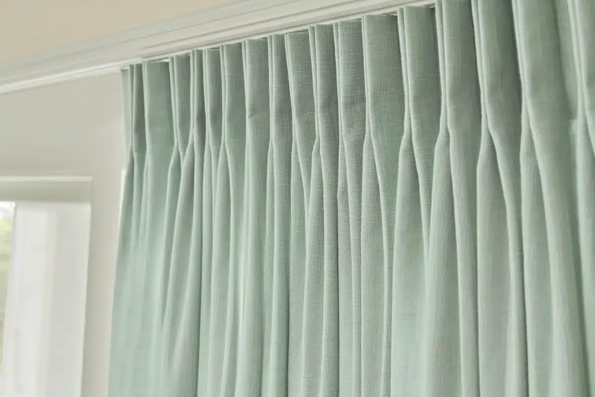 Elegant gray linen drapery panels with pinch pleats hanging from a white rod in Venice, FL