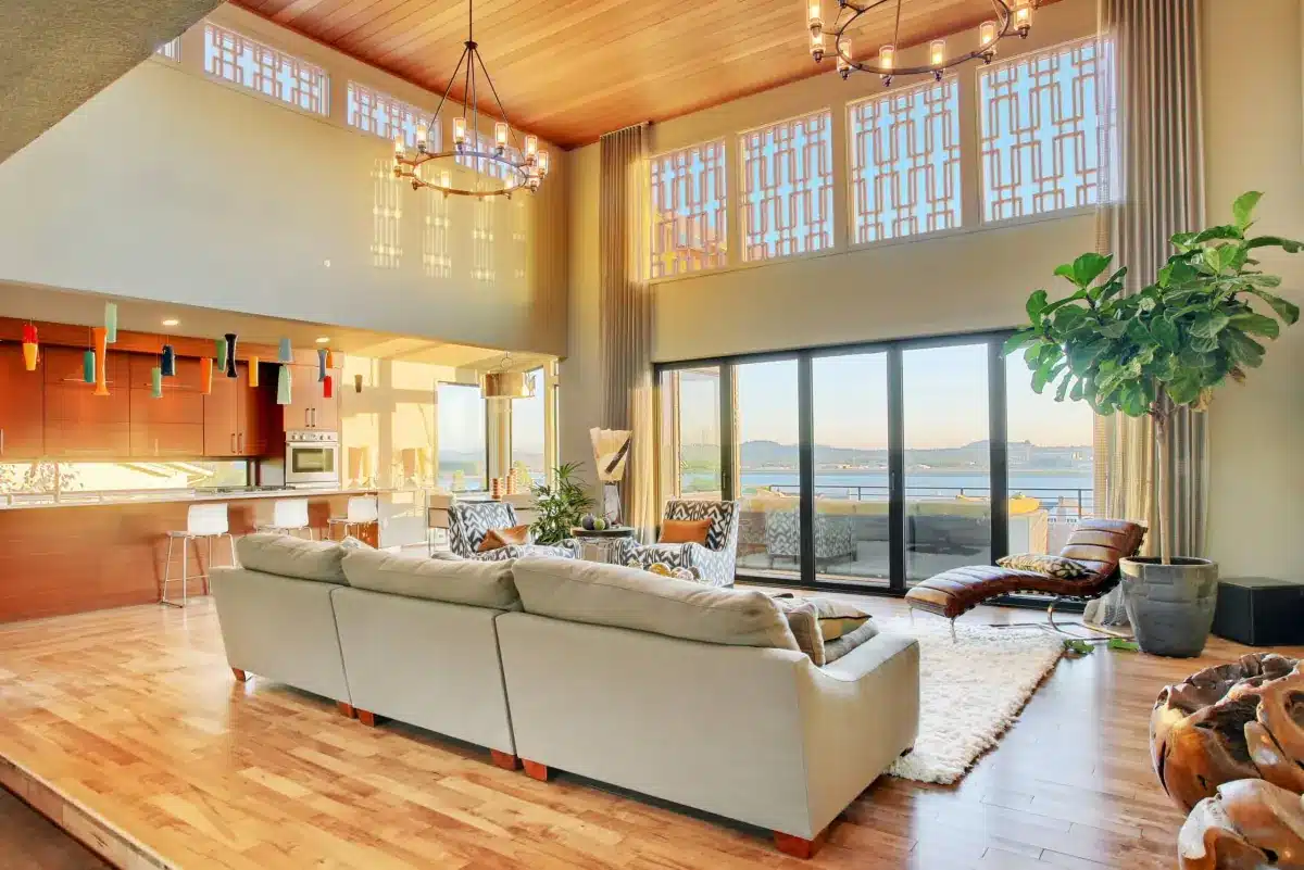 Cream drapery panels frame floor-to-ceiling windows overlooking a bay in a modern living room in Venice, FL