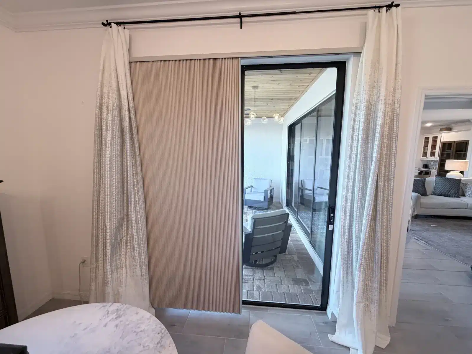 Sheer curtains hung over vertical blinds framing a bedroom sliding glass door to patio in Venice