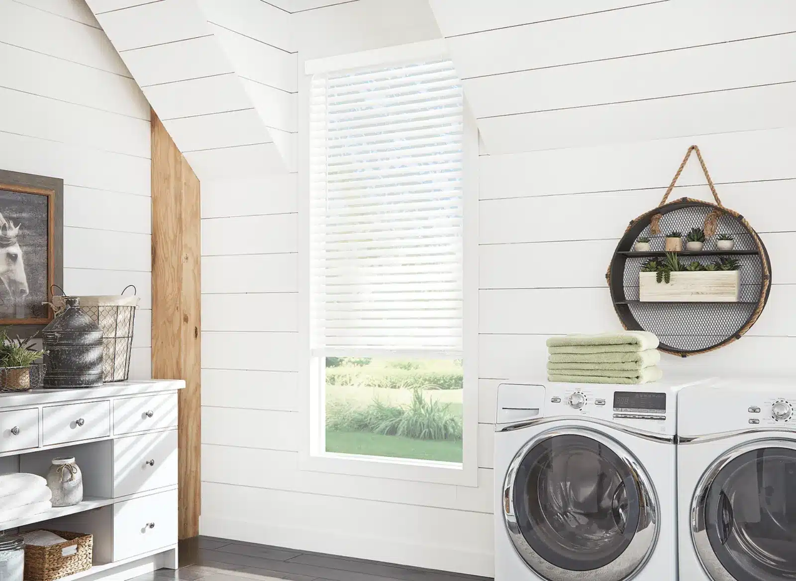 White faux wood blinds installed on a window in a bright laundry room with washer and dryer in Venice White faux wood blinds installed on a window in a bright laundry room with washer and dryer in Venice