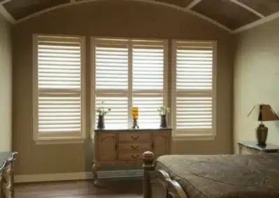Bedroom with white plantation shutters on large windows and arched coffered ceiling in Venice, FL