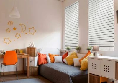 White plantation shutters in a bright bedroom with orange accents and colorful pillows in Venice, FL