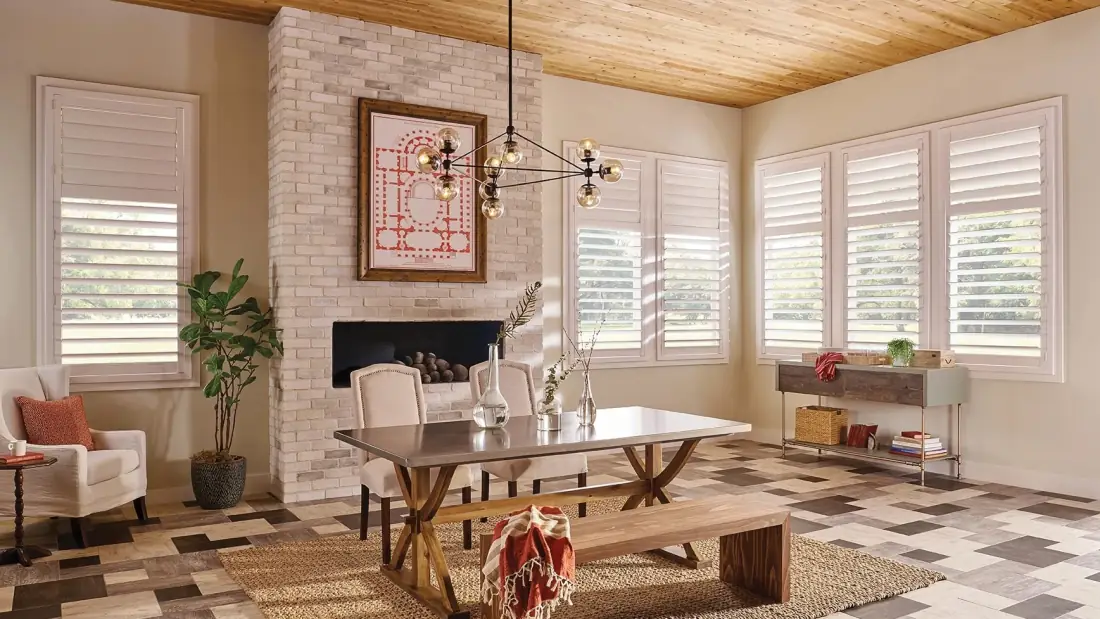 Bright living room with white plantation shutters framing windows, brick fireplace, and modern furnishings in Venice Bright living room with white plantation shutters framing windows, brick fireplace, and modern furnishings in Venice