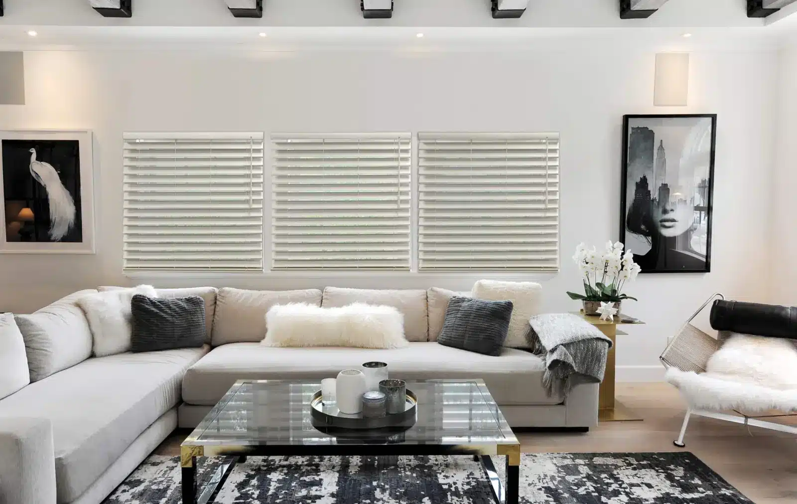 Modern white plantation shutters on three large windows above a cream sectional sofa in a contemporary living in Venice, FL Modern white plantation shutters on three large windows above a cream sectional sofa in a contemporary living in Venice, FL