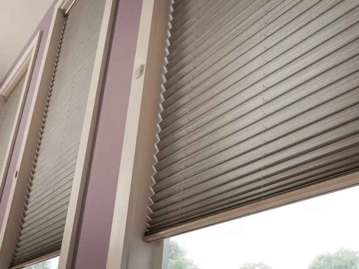 Gray pleated cellular shades installed on windows with view of outdoor landscape in Venice, FL