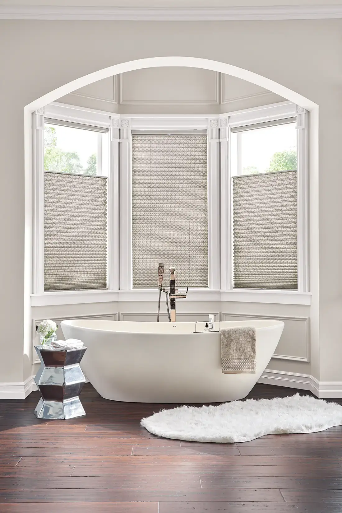 Cellular shades on an arched bay window above a freestanding tub in a luxury bathroom in Venice, FL