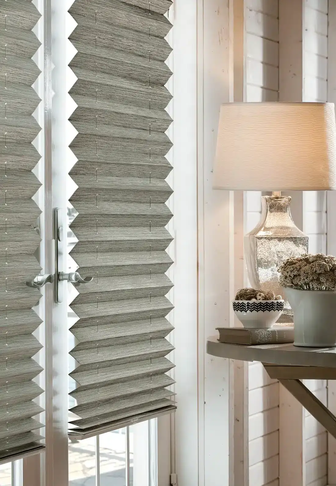 Gray pleated cellular shades on a window beside a desk with lamp and decorative accessories in Venice, FL