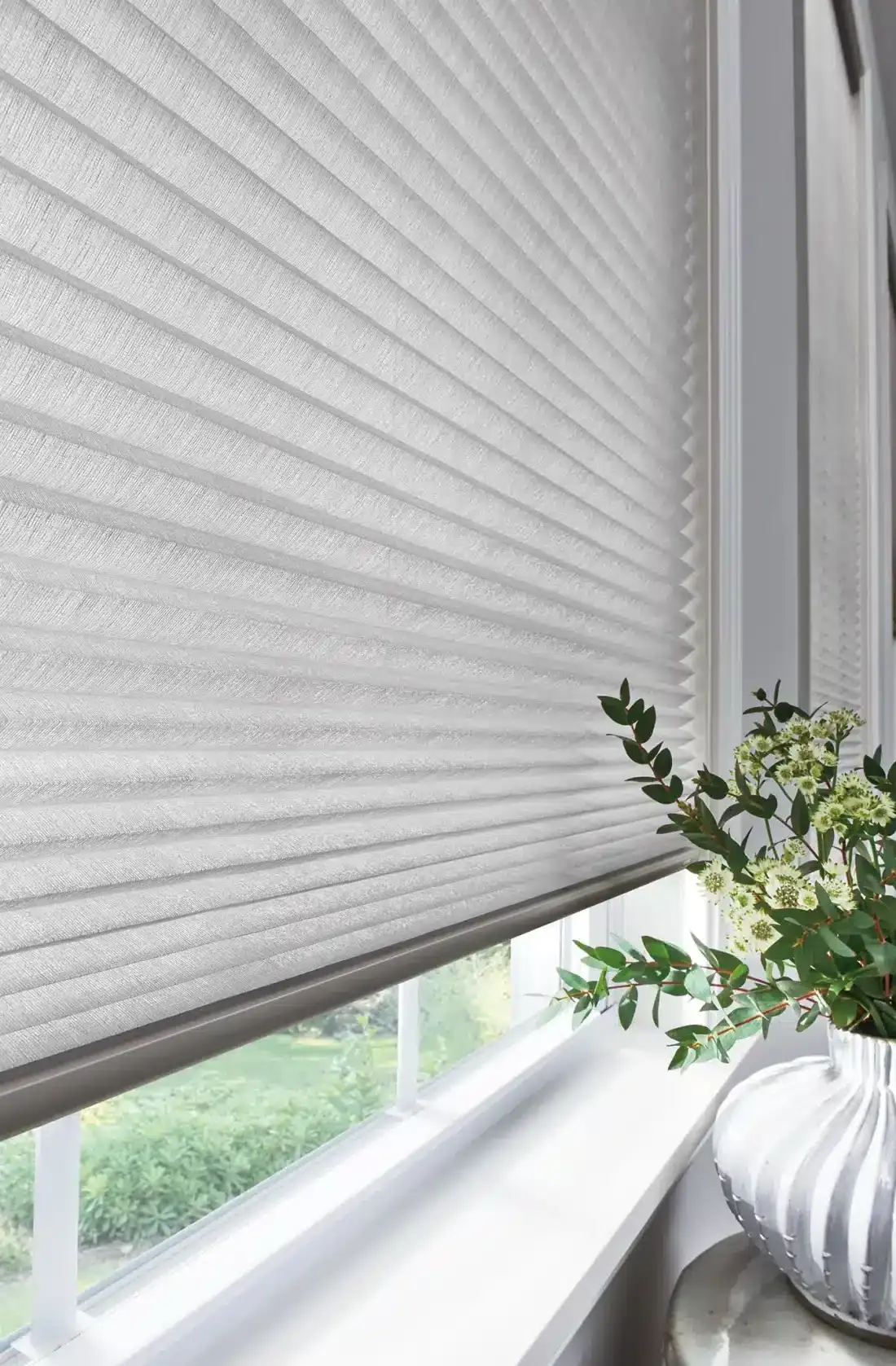 White pleated cellular shades on a window with a potted plant on the sill in Venice, FL