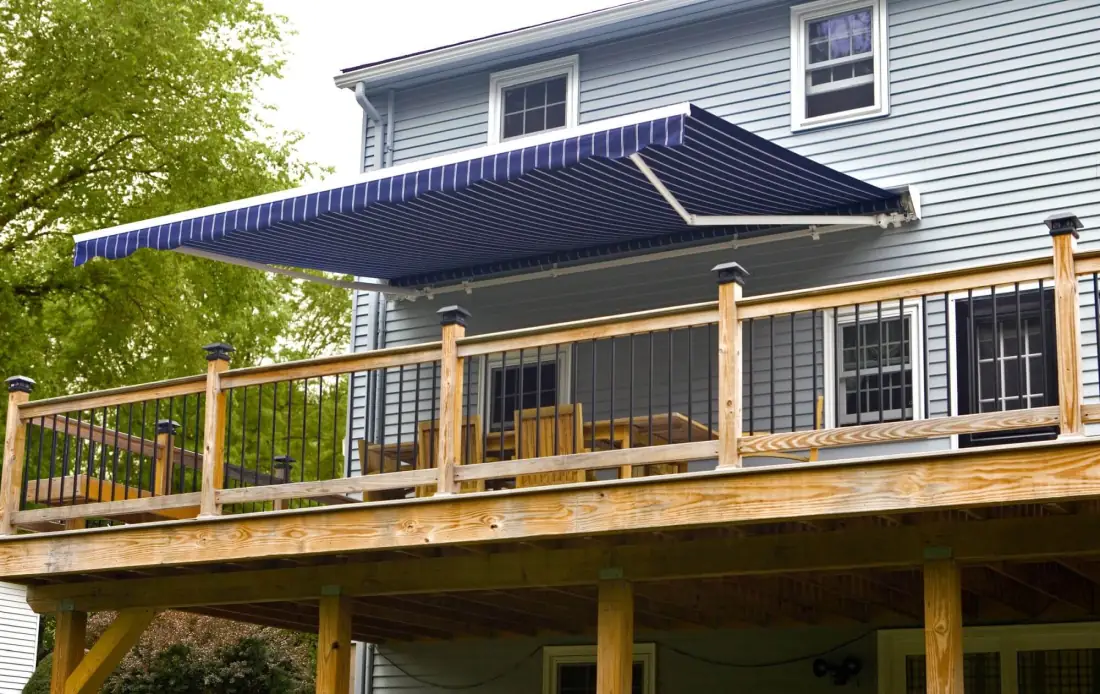 Navy blue retractable awning extending over a wooden deck with metal railings and glass panels in Venice, FL
