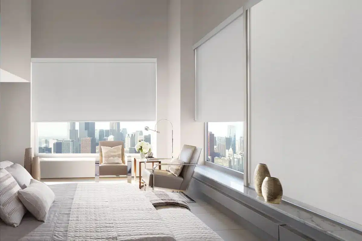 Modern bedroom with white roller shades overlooking a city skyline from a high-rise window in Venice, FL