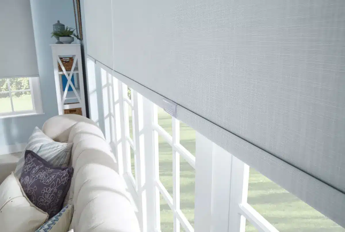 Gray roller shade in sunroom with white railing and comfortable seating in Venice, FL