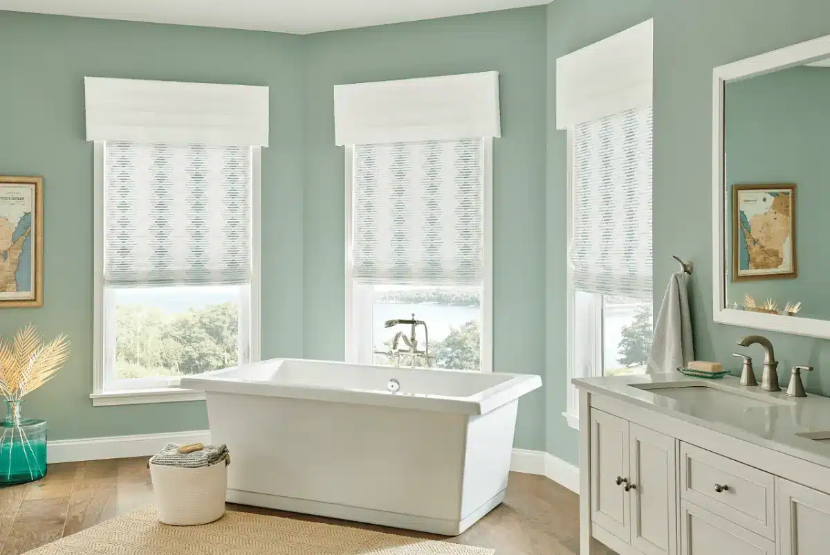 White roman shades with striped pattern hang above a freestanding tub in a spa-like bathroom in Venice, FL