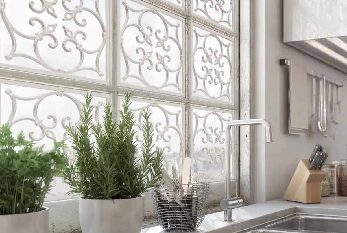 Decorative white window grille with ornamental scrollwork above a kitchen sink with potted herbs in Venice, FL