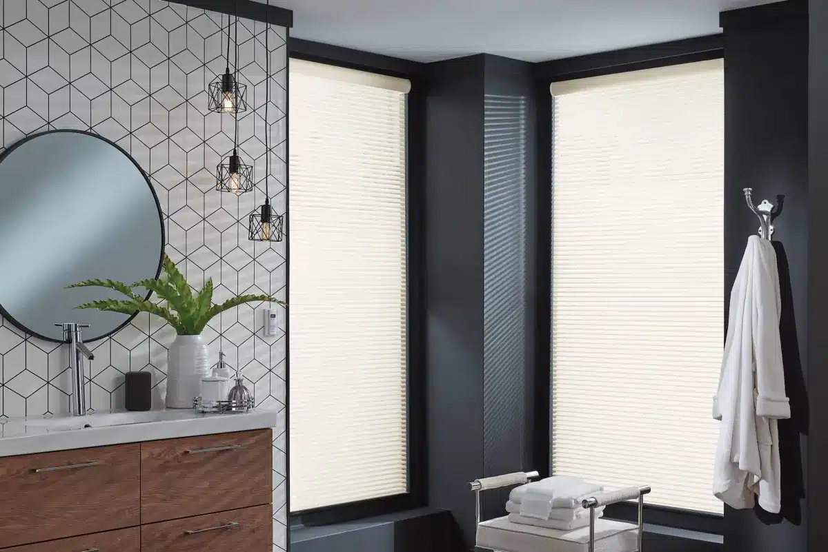 Modern bathroom with cellular shades on large windows, geometric tile wall, and wood vanity in Venice, FL