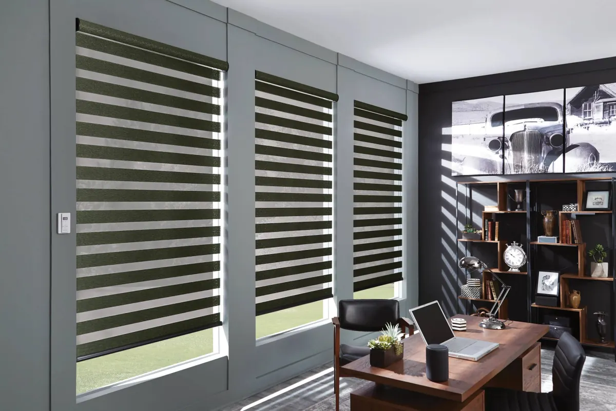 Green and white striped solar shades filter natural light in a modern home office with wooden desk and shelving in Venice, FL