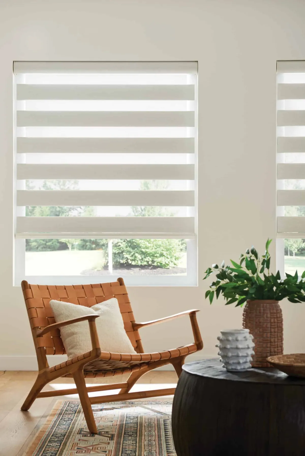Modern living room with layered solar shades filtering natural light over a wooden armchair in Venice, FL