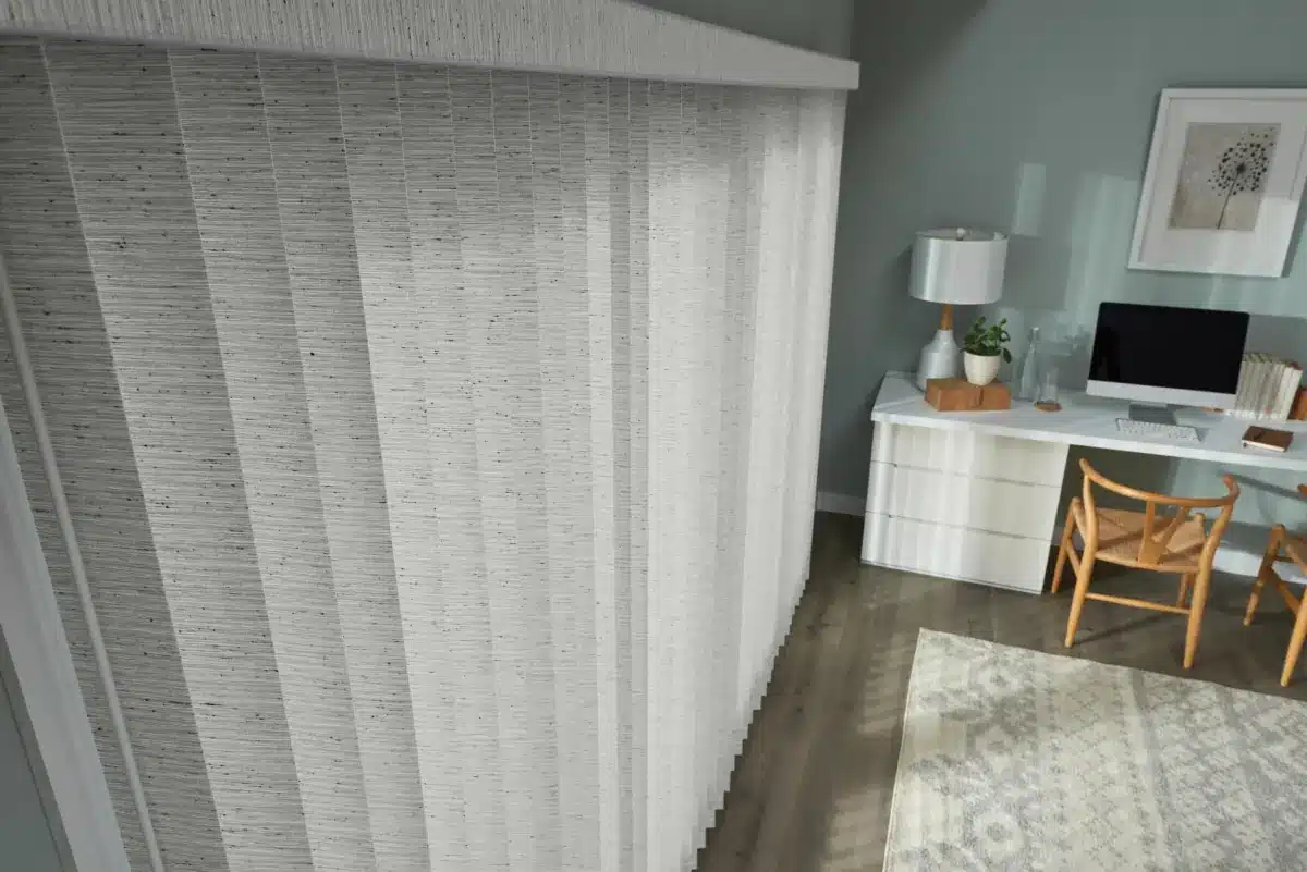 White vertical blinds with subtle texture covering a large window in a bright home office space in Venice, FL