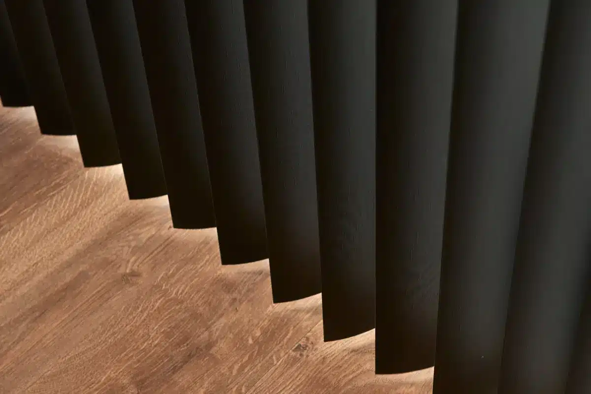 Charcoal vertical blinds casting shadows over warm wood flooring in perspective view in Venice, FL