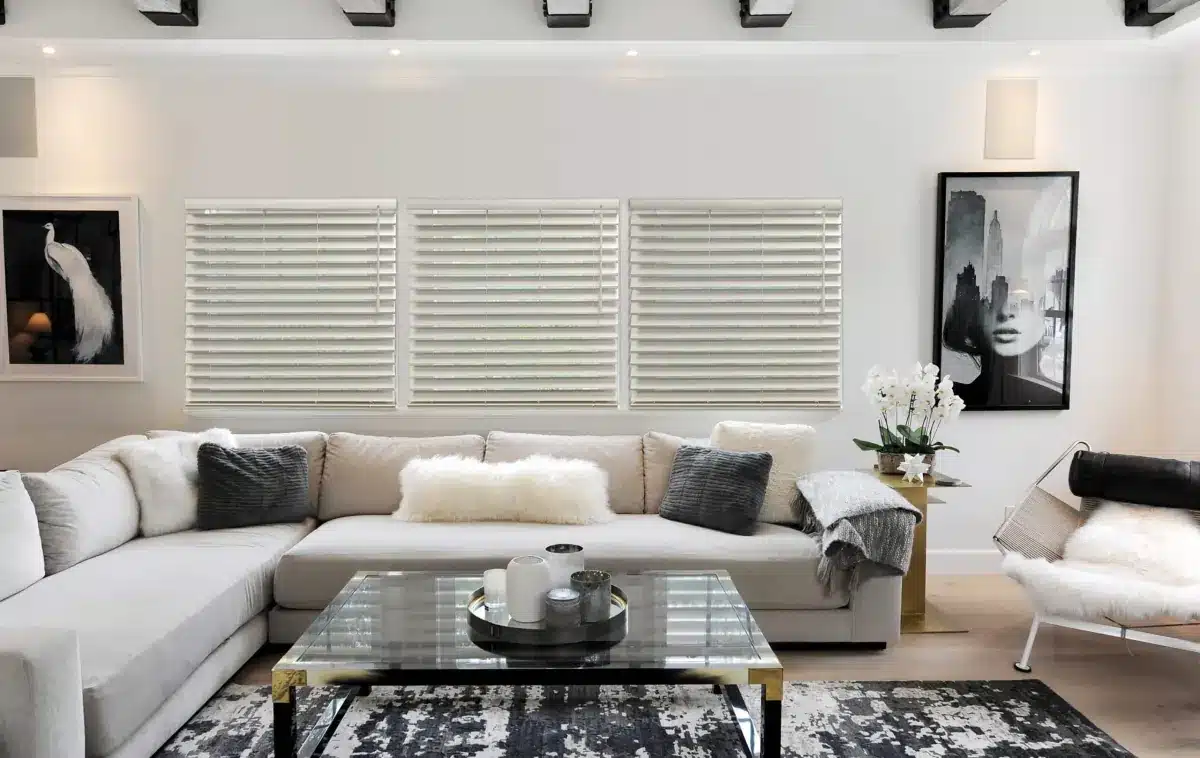 Modern living room with white faux wood blinds on large windows above a beige sectional sofa in Venice, FL