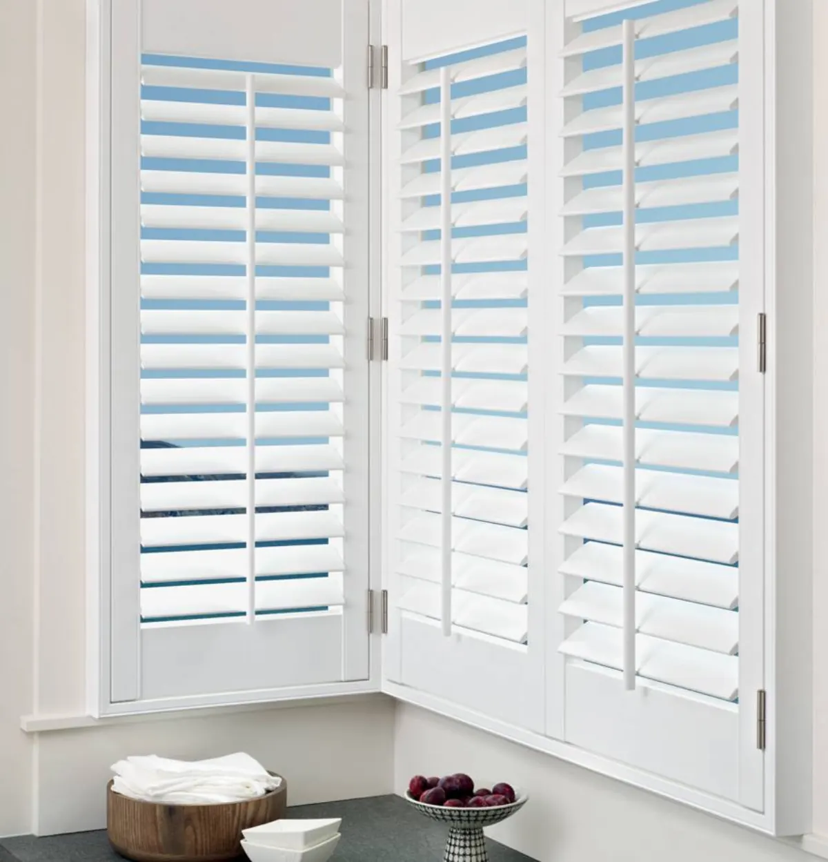 White faux wood shutters with blue and white slats partially open on corner windows in Venice, FL