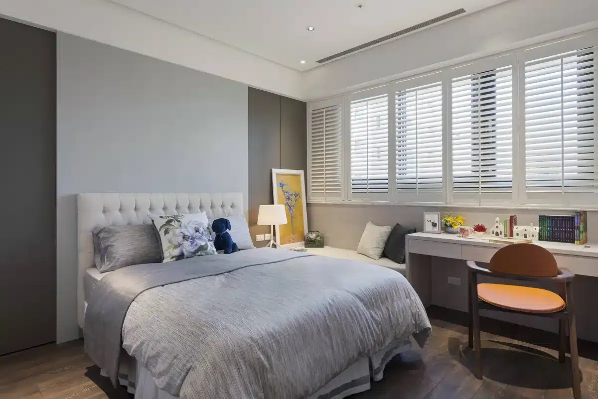Modern bedroom with white plantation shutters covering large windows above a desk area in Venice, FL