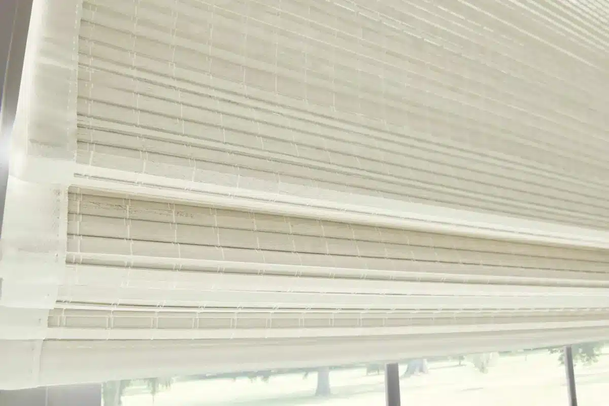 Close-up of cream woven wood shades partially lowered over a bright window in Venice, FL