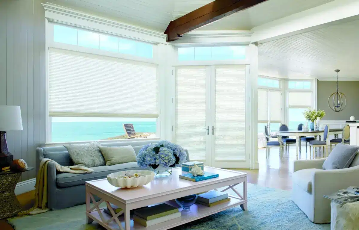 Woven wood shades filter light in a bright coastal living room overlooking the beach in Venice, FL