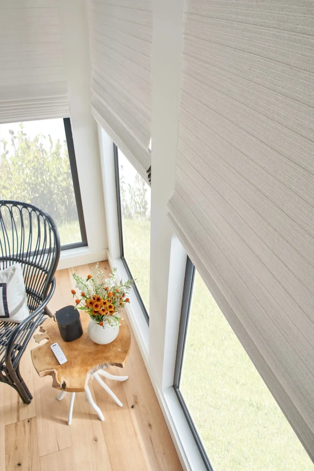 Woven wood shades filter natural light in a bright sunroom with garden views and modern furnishings in Venice, FL