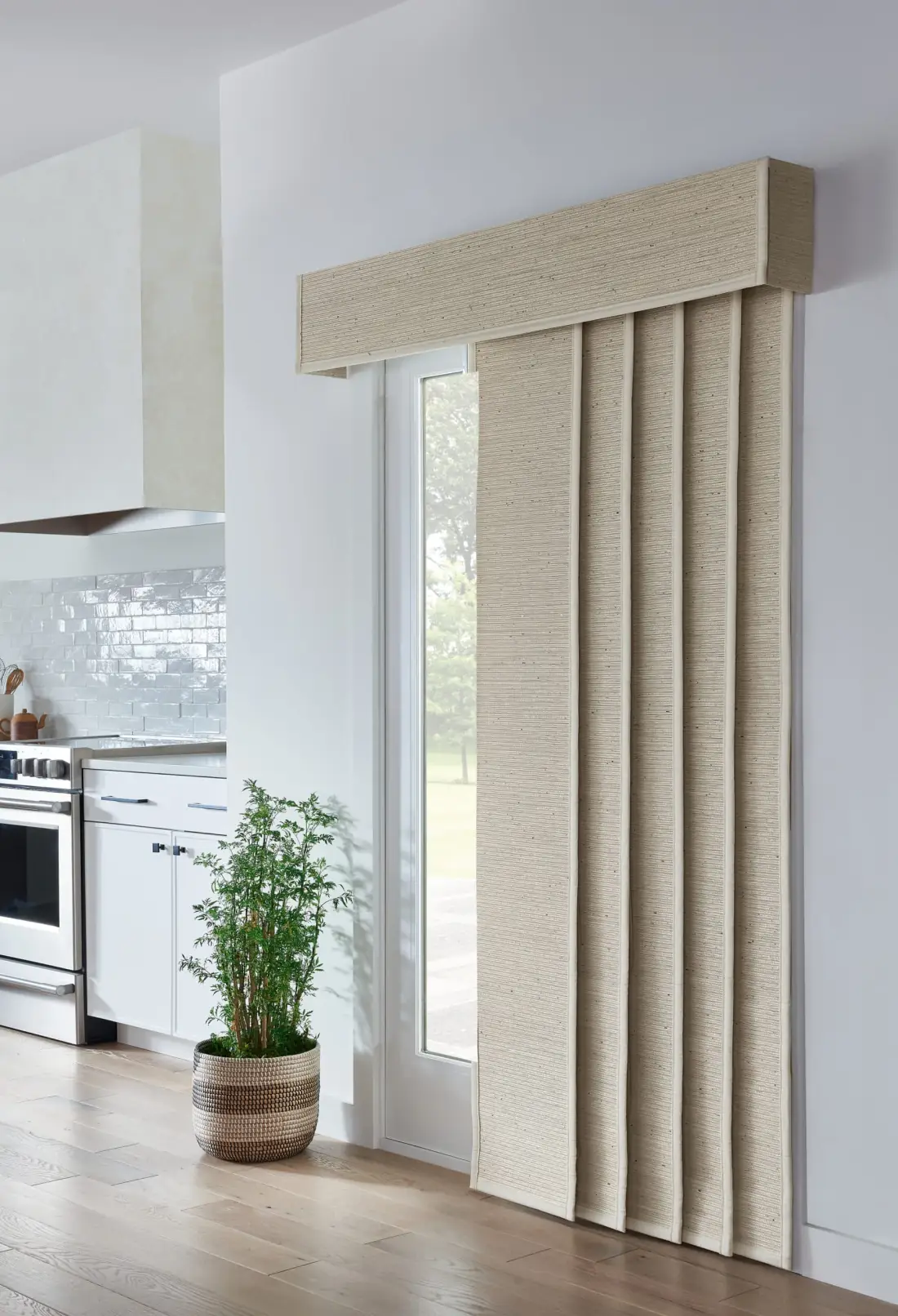 Woven wood shades in natural tone covering a kitchen patio door with soft daylight filtering through in Venice, FL